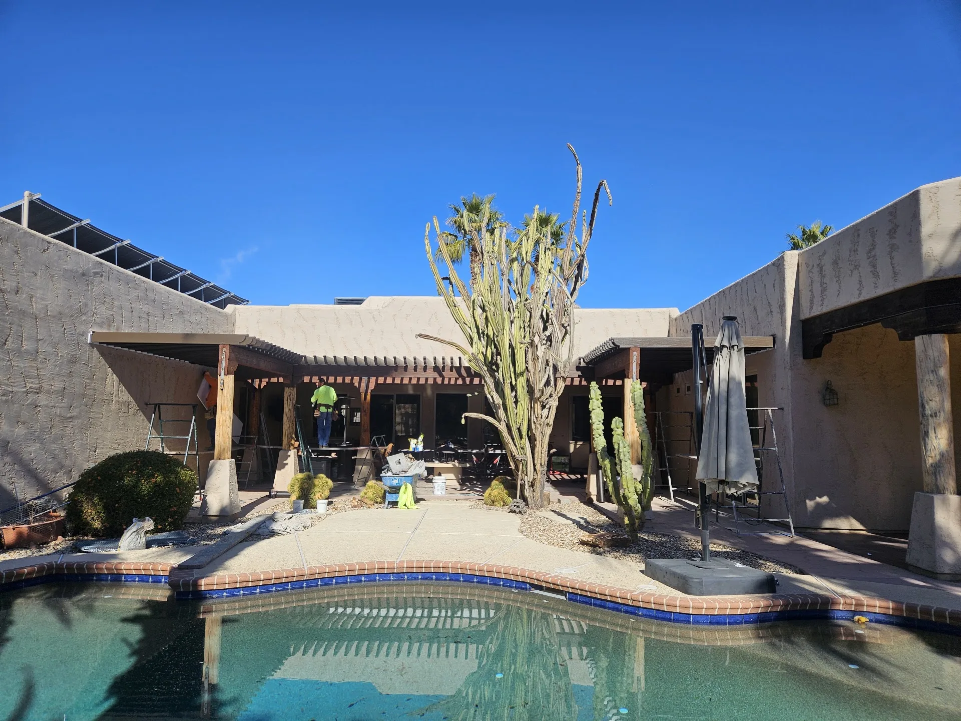 Freestanding shade structure over an outdoor kitchen beside a pool